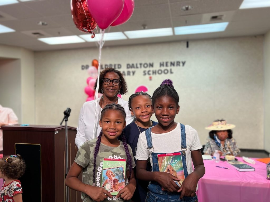 Photo caption: Library Foundation Board Secretary Debra A. Fields presents books to Serinitee-Love Taylor, Samauri-James Thompson, and Trinity-Rose Thompson at the American Girl Doll “Tea Party."