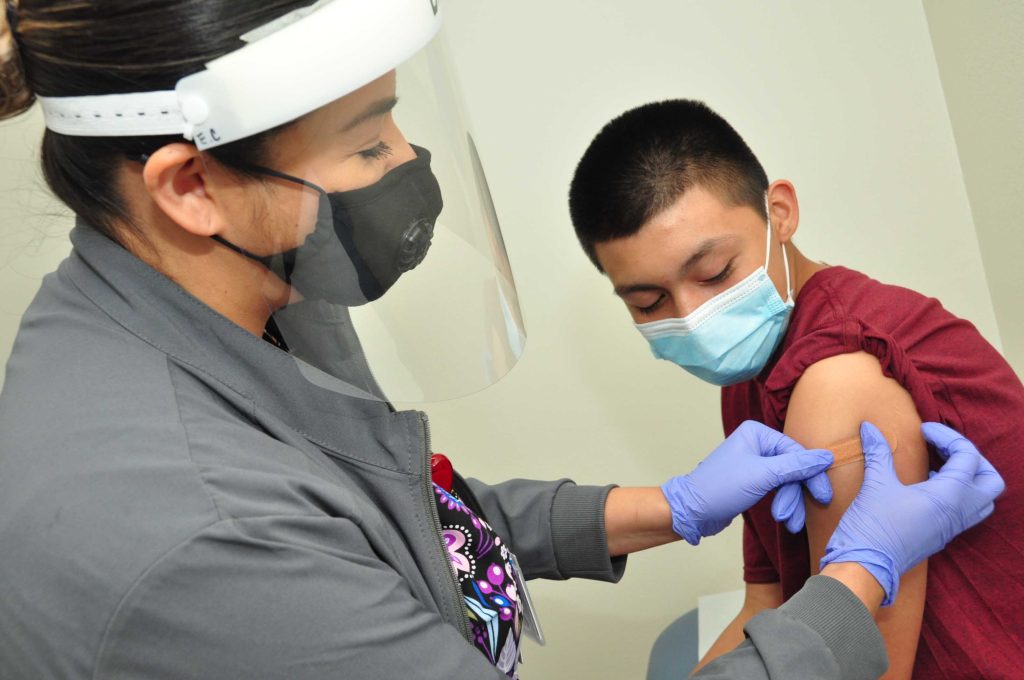 Photo Caption: Nurse Elisabeth with gives patient Eduaido Torres age 13 a vaccine. 